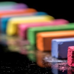 Close up row of colorful chalk isolated on black background. Macro photography. Cut out