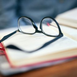 Closeup shot of reading glasses on an open book on a university desk indoors